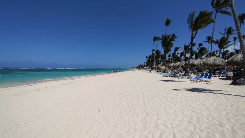 The wide, sandy beach at Majestic Resort with palm trees and turquoise waters
